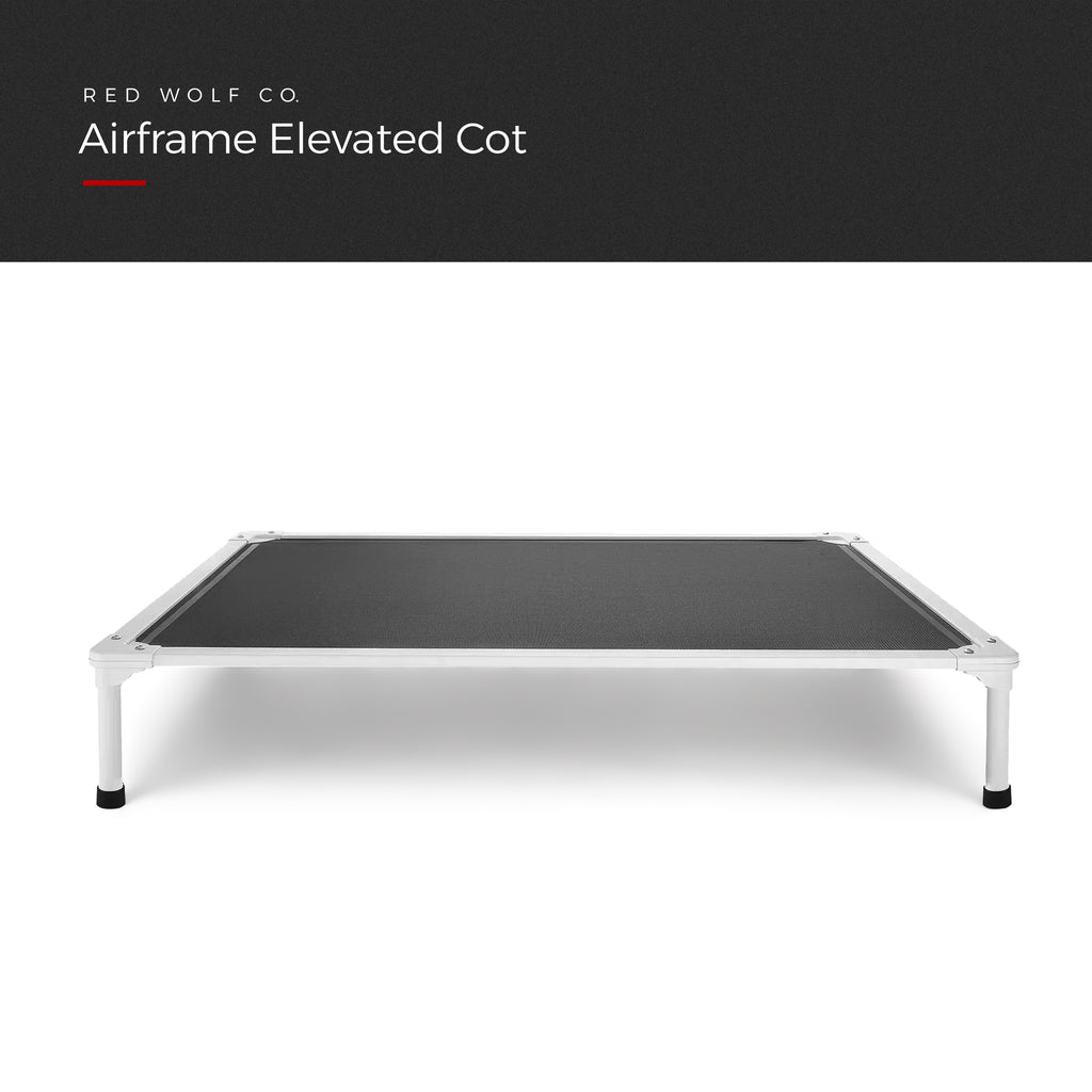 Airframe Elevated Cot with a dark grey mesh bed on a light aluminum frame with black feet, front view, under a Red Wolf Co. title banner
