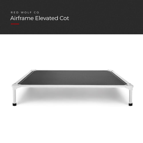 Airframe Elevated Cot with a dark grey mesh bed on a light aluminum frame with black feet, front view, under a Red Wolf Co. title banner