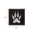 Embroidered white dog claw print patch on black backing, 50 mm square, with hook velcro reverse